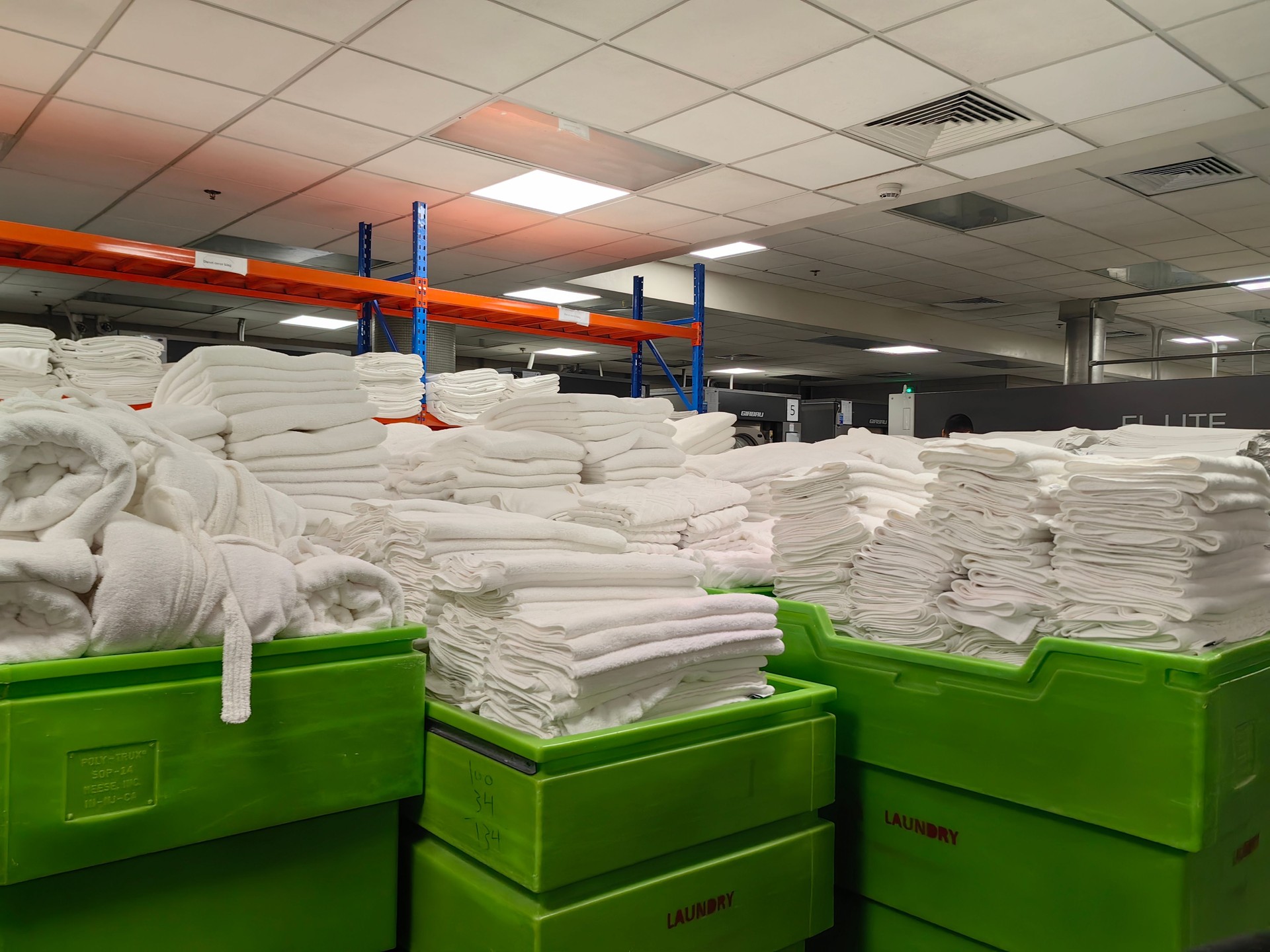 White blankets, pillow cases, hotel room equipment neatly and cleanly arranged in the laundry room.
